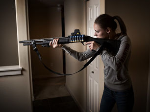 A homeowner holding a home defense shotgun inside a house, demonstrating a common firearm option for home protection.
