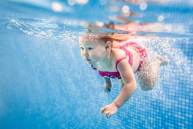 Little baby, girl swimming under water in paddling pool. Diving baby. Learning infant chil