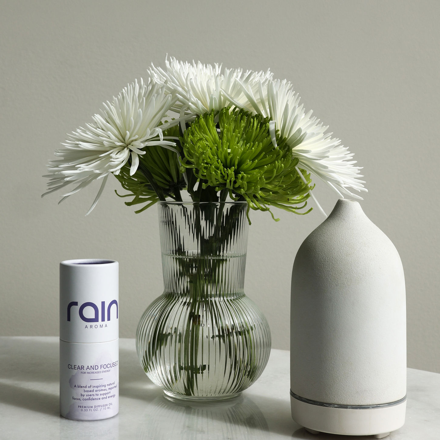 Clear and focused diffuser oil with diffuser and vase of flowers.