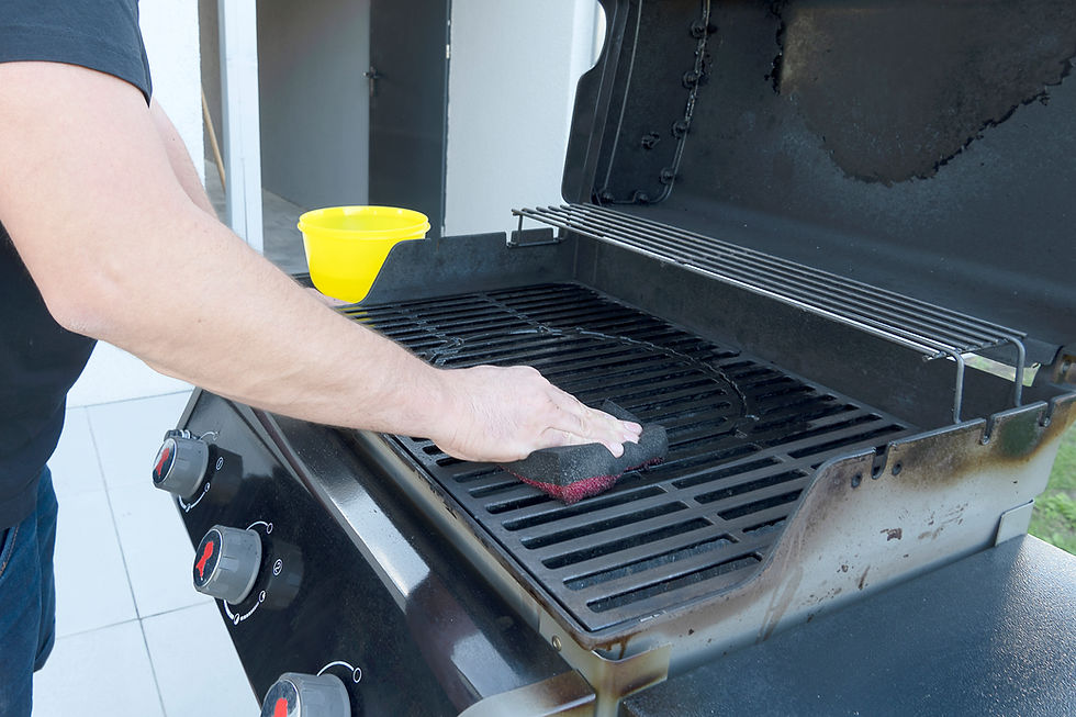 Side view of a grill being cleaned with a wire brush, showing the grill hood lifted and interior grates.