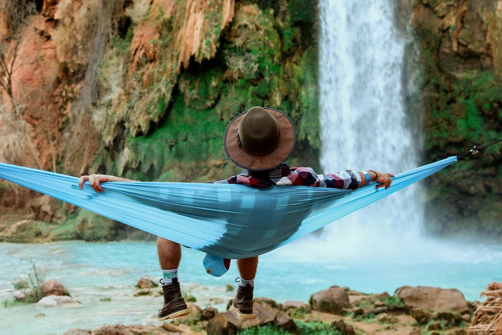 Man in a hammock beside a waterfall.