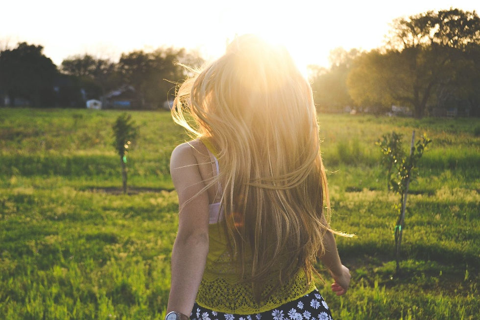 Woman in a grass field looking at the sun.