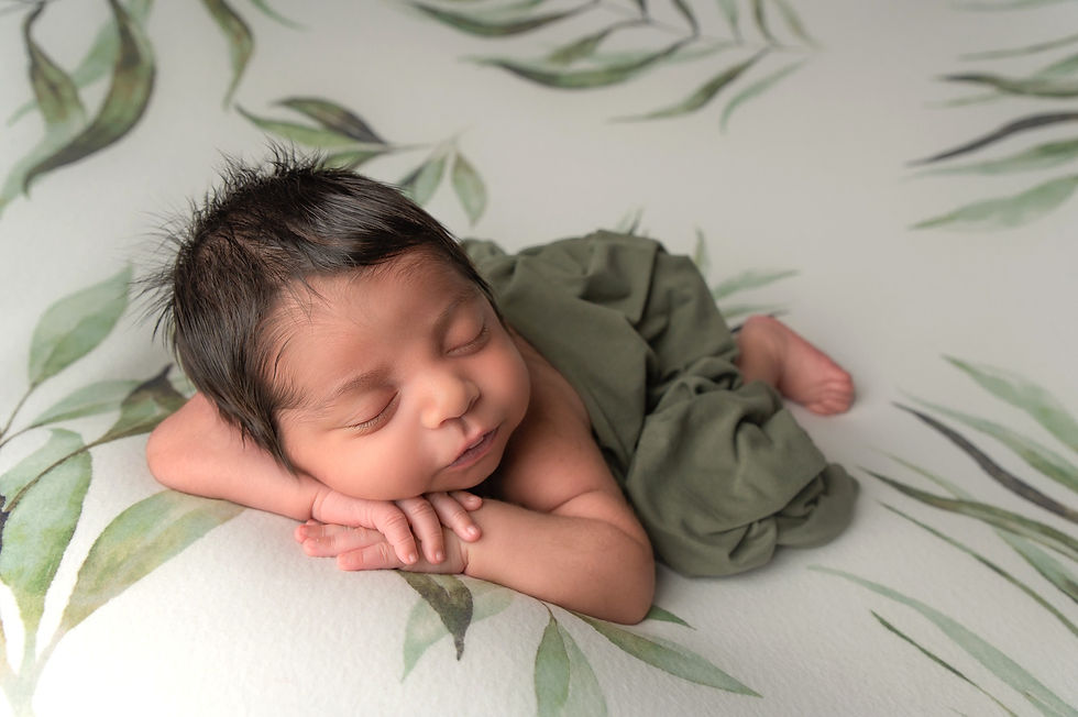 newborn baby boy with lots of dark hair resting on his belly, sleeping soundly