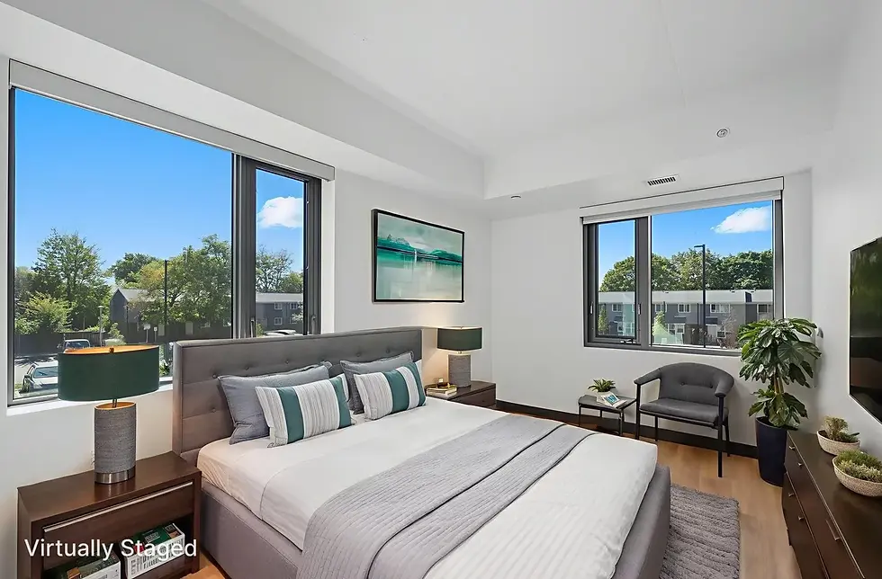 Modern bedroom with a grey bed, teal accents, two lamps, and large windows overlooking trees. "Virtually Staged" text in the corner.