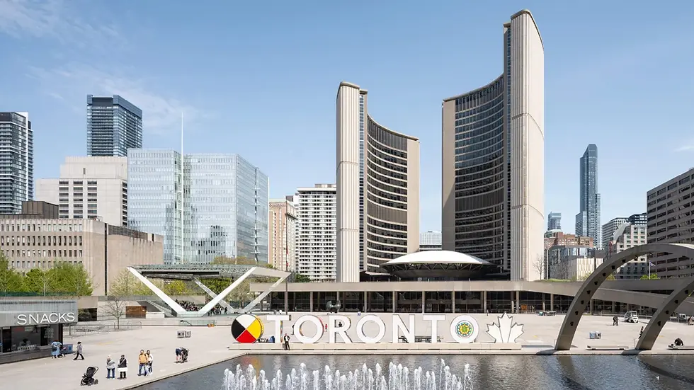 Toronto City Hall under a clear sky, with a fountain in foreground and "TORONTO" sign. People walk nearby. Urban skyscrapers surround.