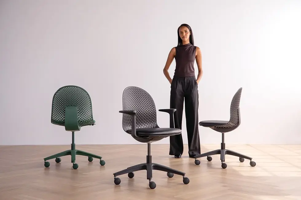 A person stands beside three modern office chairs in green and black on a wooden floor, with a neutral wall background, conveying a sleek mood.