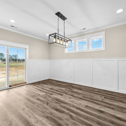 Modern dining room with wood floors and sliding glass door overlooks landscape