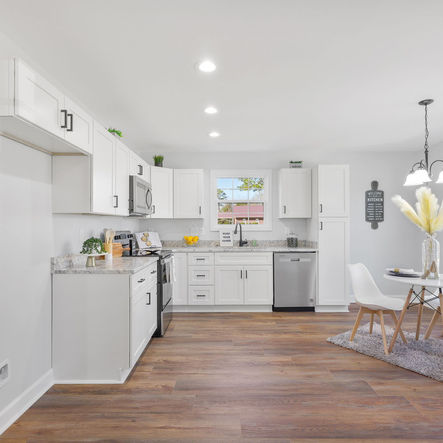 Modern kitchen with white cabinets and stainless steel appliances; spacious design.