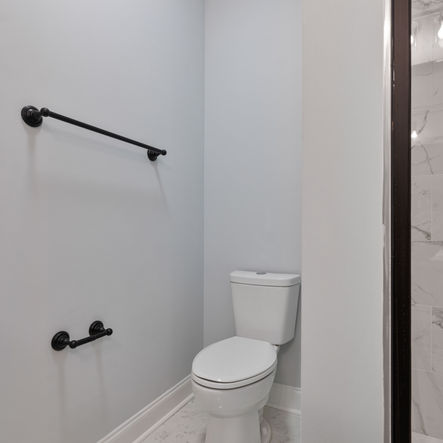 Clean bathroom design with a white toilet and black fixtures. T&C Construction Group LLC