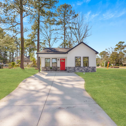Exterior view of a newly built home, red door, and green lawn custom home builder north carolina