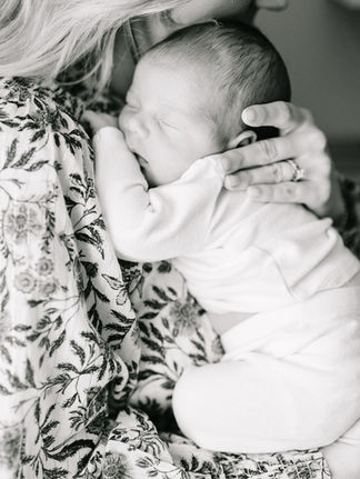 Parent holding newborn baby near a window during an in-home newborn photography session in Minnesota