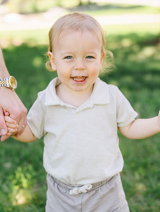 little boy holding parents hands at family photoshoot in plymouth minnesota