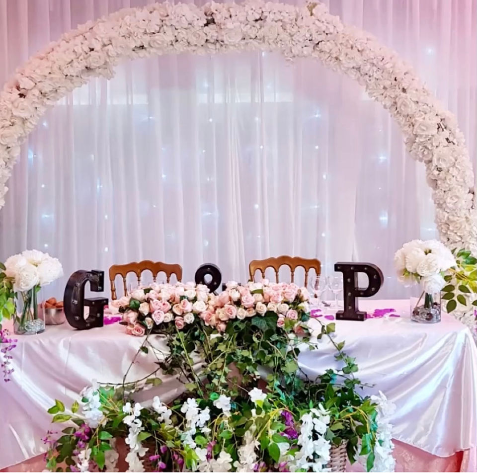 A wedding table elegantly decorated with a large bouquet of flowers and the letters ‘g & p’, creating a festive and romantic atmosphere for the celebration.