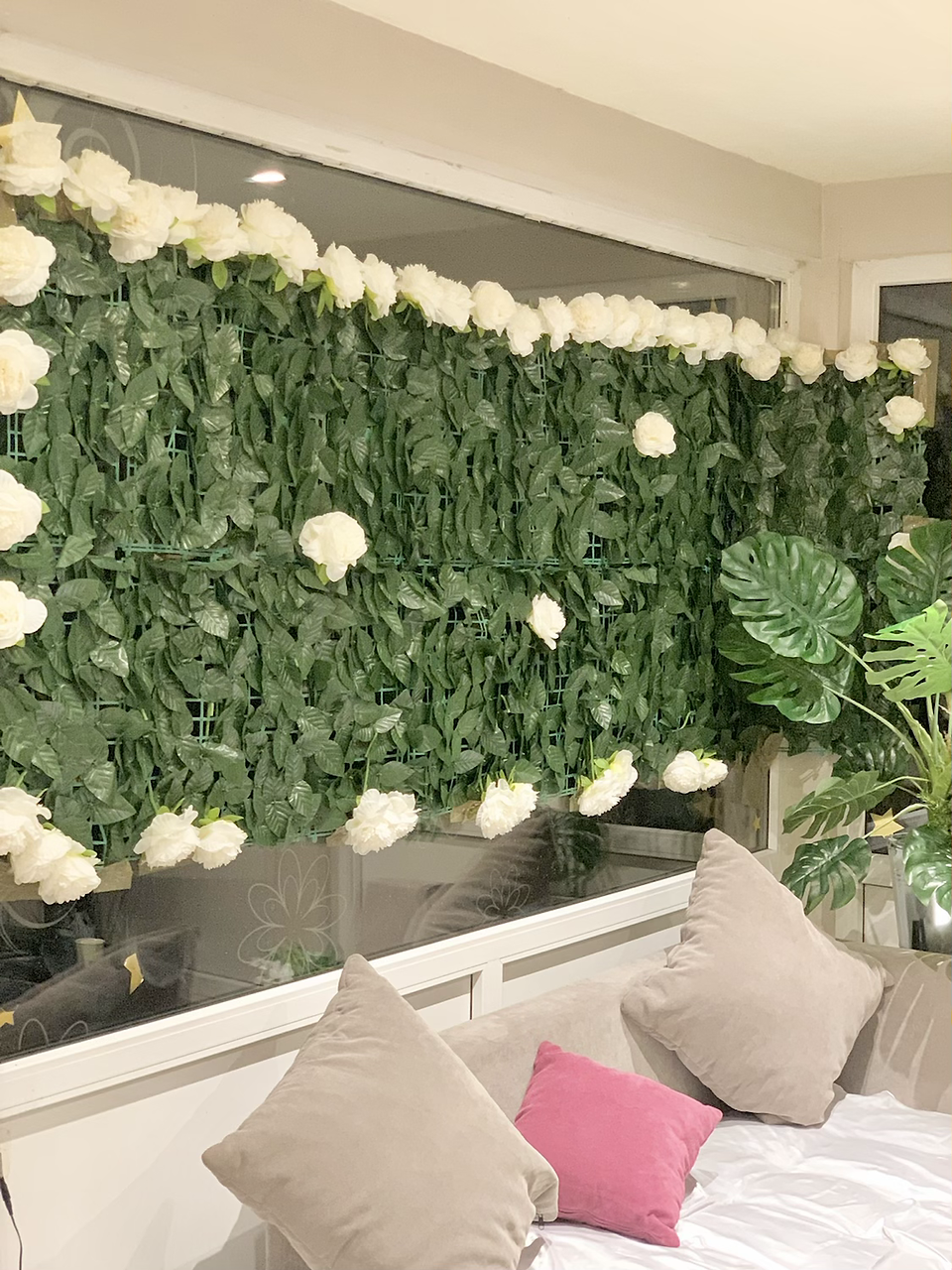 A window adorned with a wall of flowers and greenery, adding a touch of freshness to the event space, decorated for a birthday party.