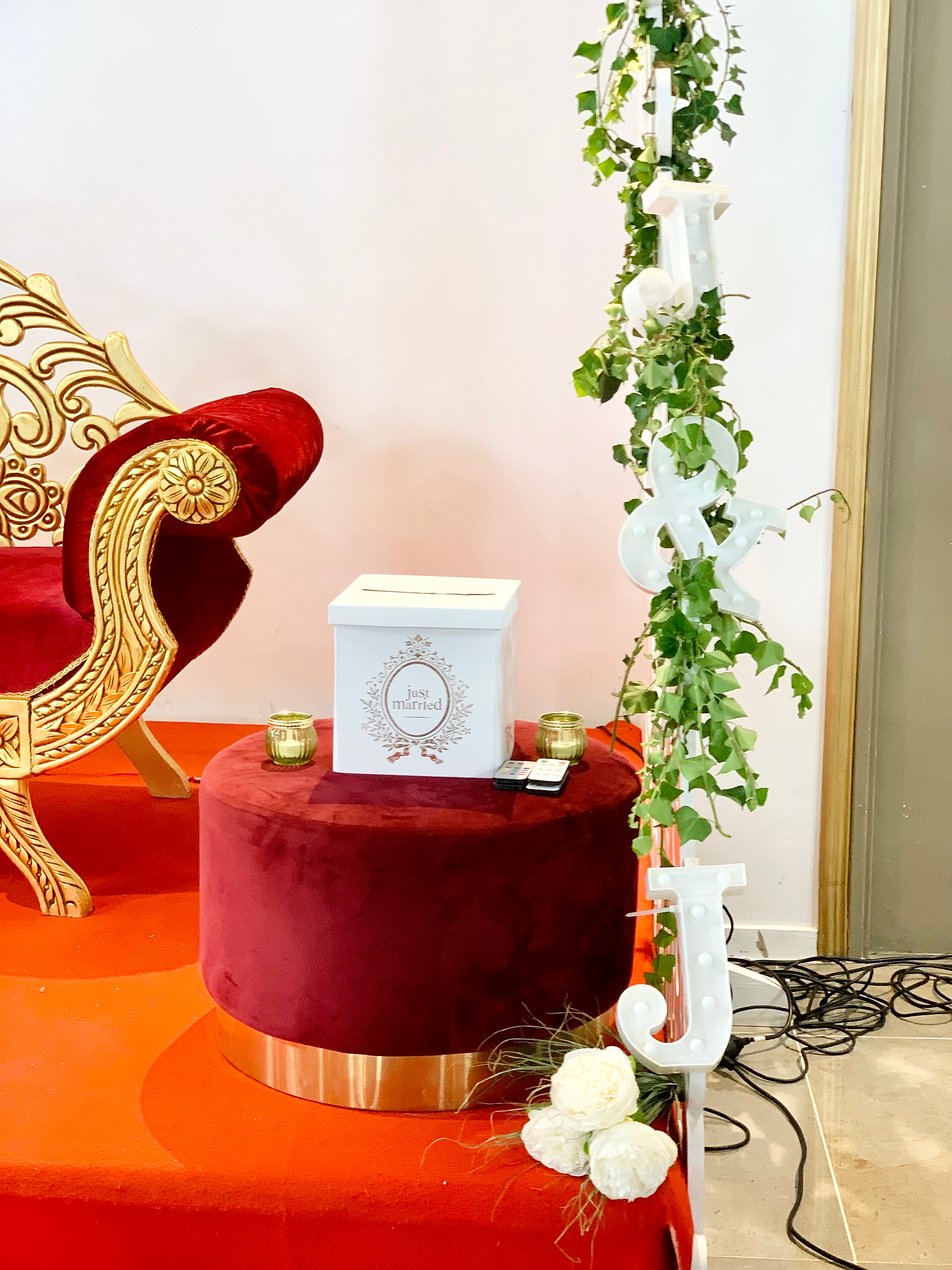 Un pouf en velours rouge, posé sur une urne de mariage, allie confort et esthétique, créant une atmosphère chaleureuse.
