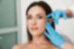 A woman receives a precise Botox injection near her eye from a professional wearing blue gloves, highlighting the process of Botox under your eyes for a smoother, youthful appearance.