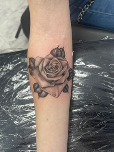 Black and gray rose tattoo on arm