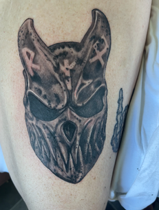 Stylized horned mask tattoo with runes