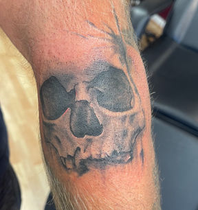 Black and grey skull tattoo on arm