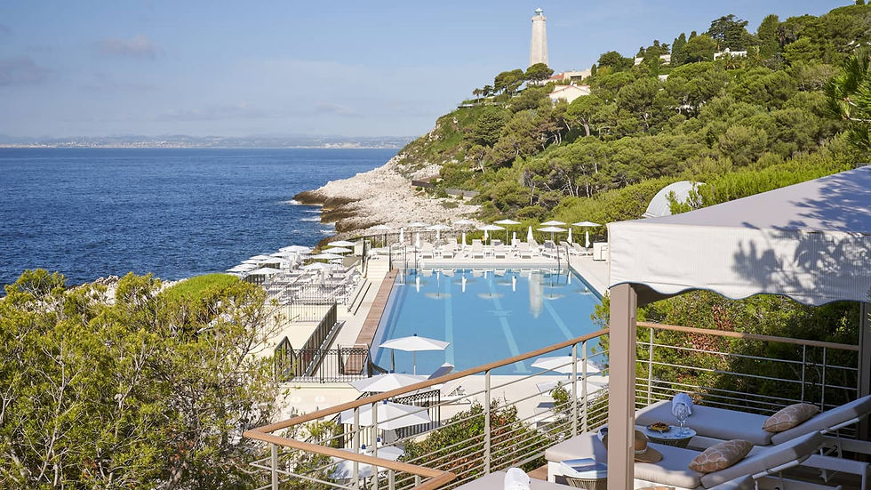 Elegant seaside view of the Grand-Hôtel du Cap-Ferrat with its iconic white façade, manicured gardens, and infinity pool perched above the sparkling Mediterranean coastline.