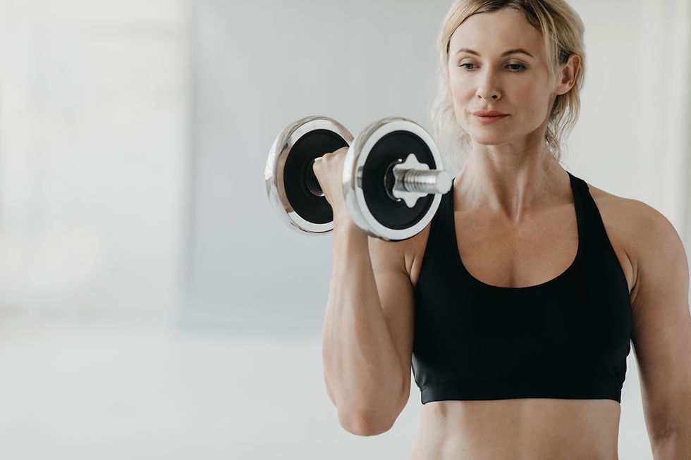 Woman in a cropped sports bra holding a single dumbbell with her arm flexed