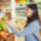 Woman selecting a fresh green apple in a grocery store.