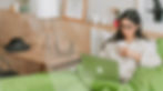 Woman using a laptop while sitting in bed with a mug.