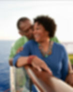 loving, mature couple leaning on a polished wooden railing of a cruise ship with open sea