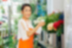 Smiling florist spraying water on fresh flower bouquets