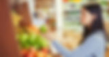 Woman selecting a green apple while grocery shopping.