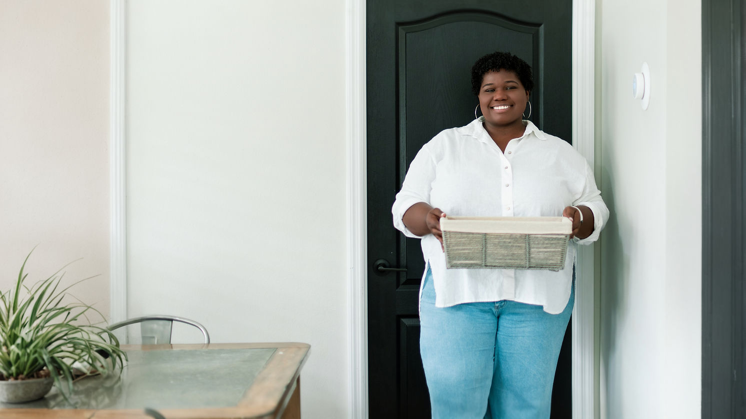 Lastree, owner of Ready Set Declutter, smiling and holding a laundry basket in a doorway