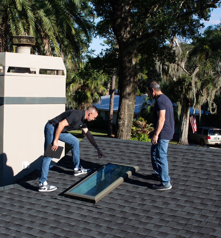 Two roofers installing a skylight on a residential roof.