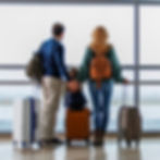 Family with luggage looking out of an airport window