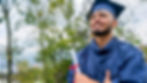 Smiling graduate in blue gown holding a diploma outdoors