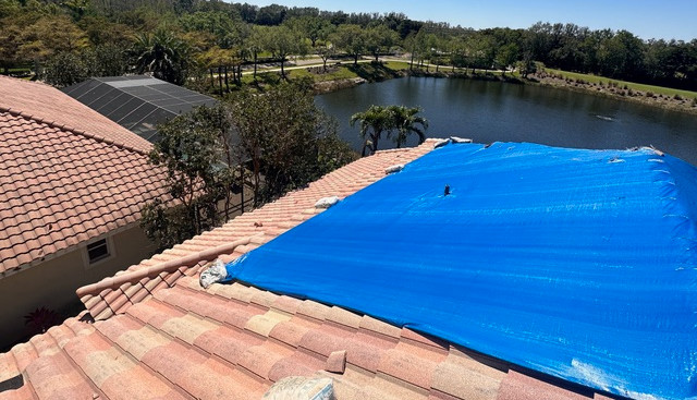 blue tarp protecting a tile shingle roof in need of repair