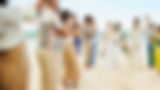 Newlyweds walking on beach while guests applaud
