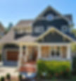 a two-story Craftsman-style house features dark siding with white trim, a covered front po