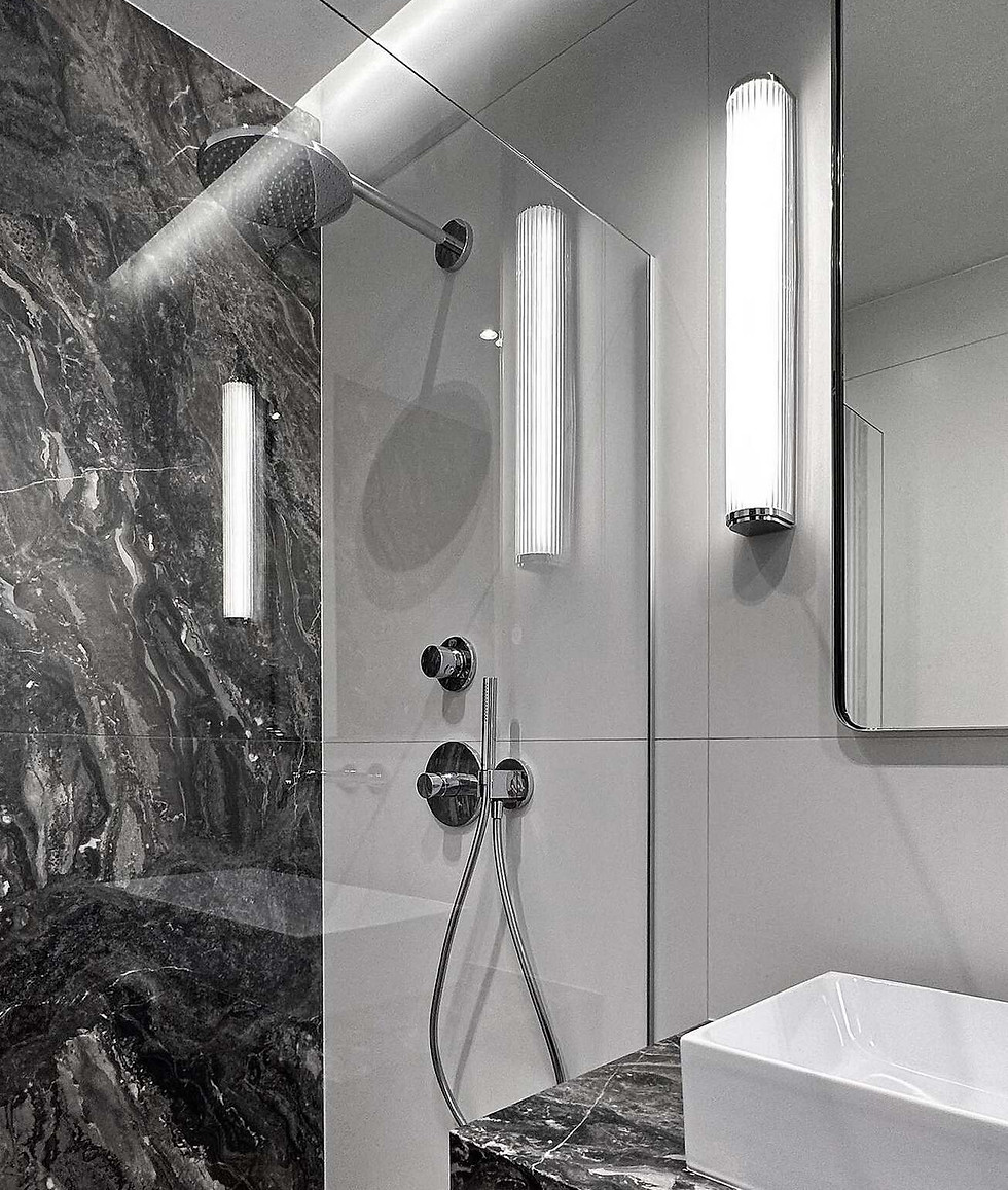 Subtelne połączenie marmuru, szkła i ciepłego światła kinkietów w nowoczesnej łazience.