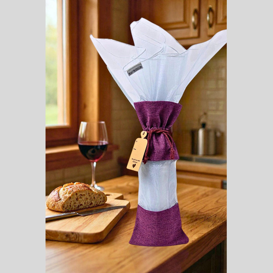 Burgundy bamboo jute wine gift bag styled on a kitchen counter with wine glass and bread in a cozy home scene.
