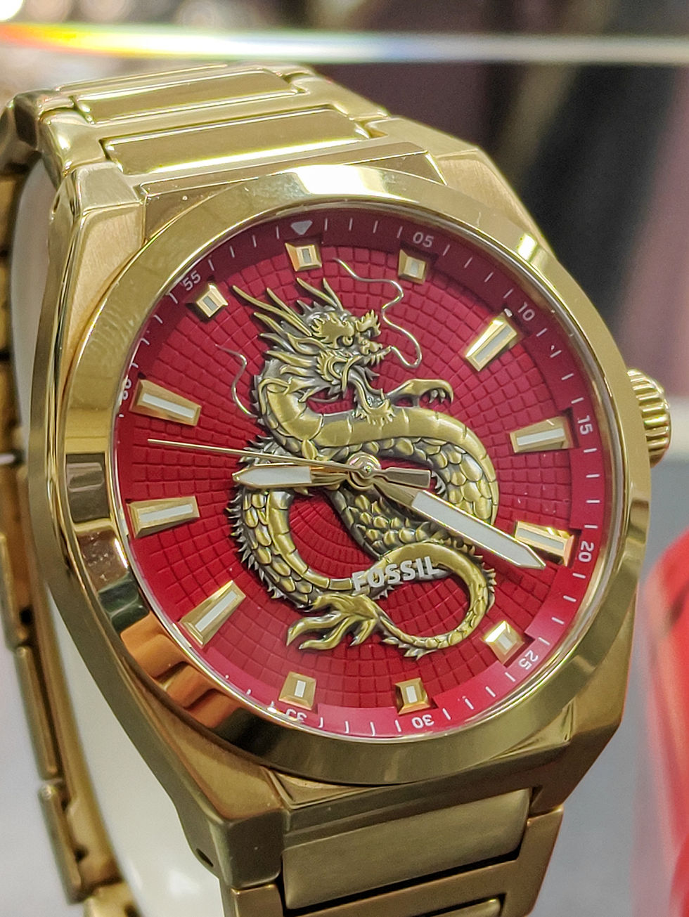 Fossil Everett FS6037 gold-tone stainless steel watch with red dragon dial, shown with original red tin box and Fossil manual
