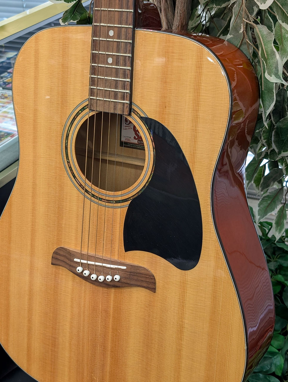 Thumbnail: Natural Oscar Schmidt by Washburn OG2TPAK dreadnought acoustic guitar showing its spruce top, black pickguard, rosewood bridg