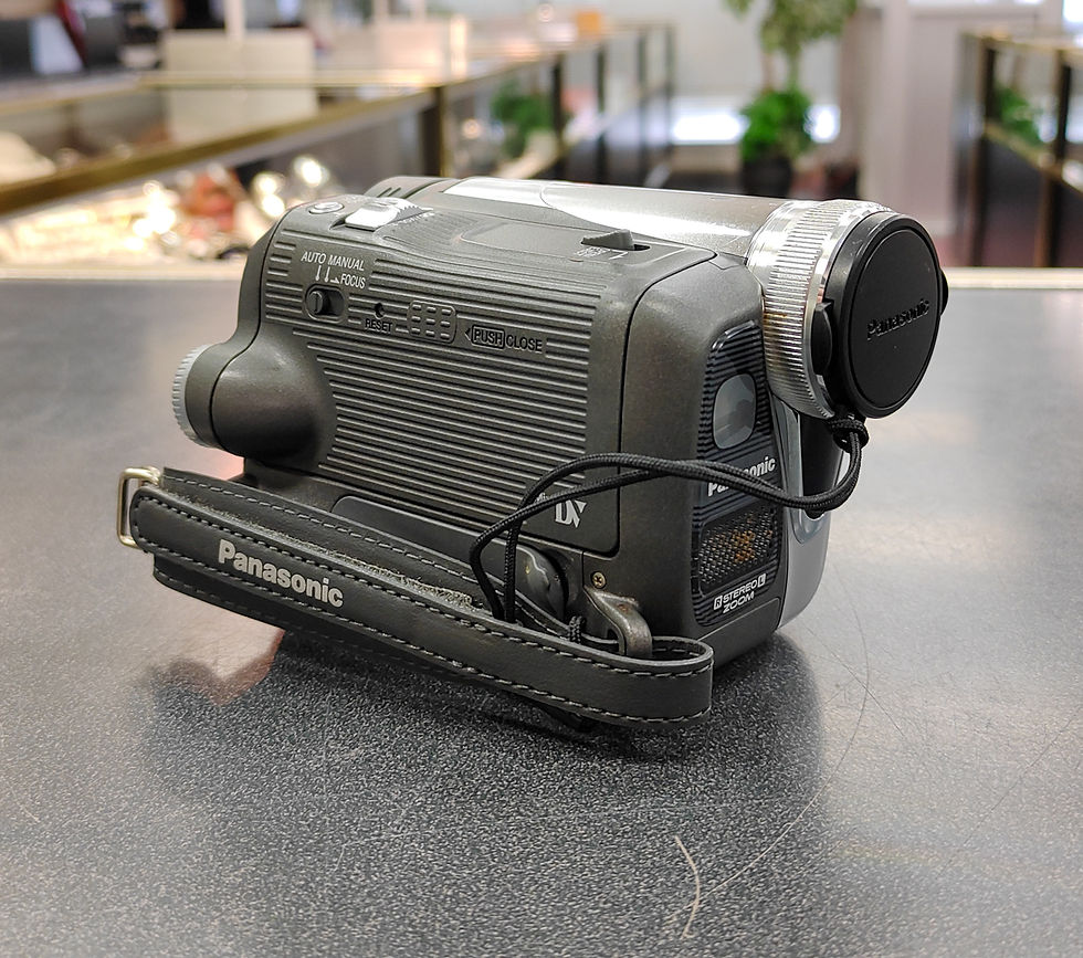 Panasonic PV-GS35 MiniDV camcorder in silver with original battery, aftermarket charger, lens cap, flip-out LCD, and cassette