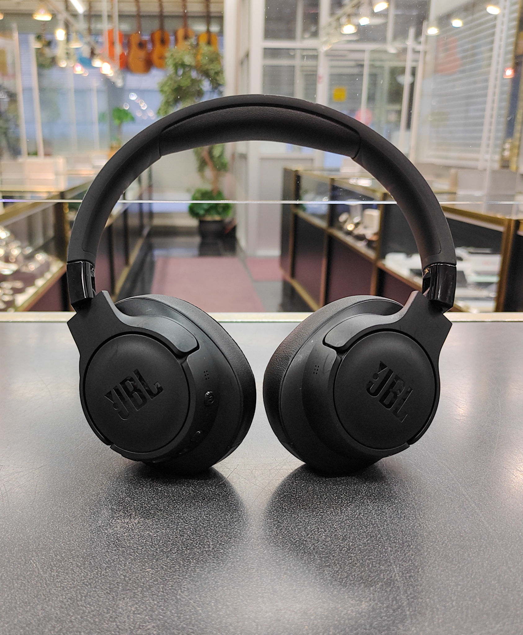 Black JBL Tune 770NC wireless over-ear headphones showing earcups, controls, minor headband surface scratches; USB charging