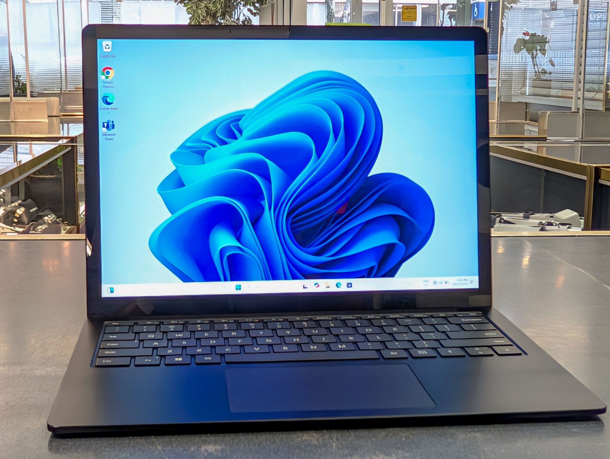 Microsoft Surface Laptop 4 in black finish powered on with Windows 11, showing clean keyboard, touchscreen display