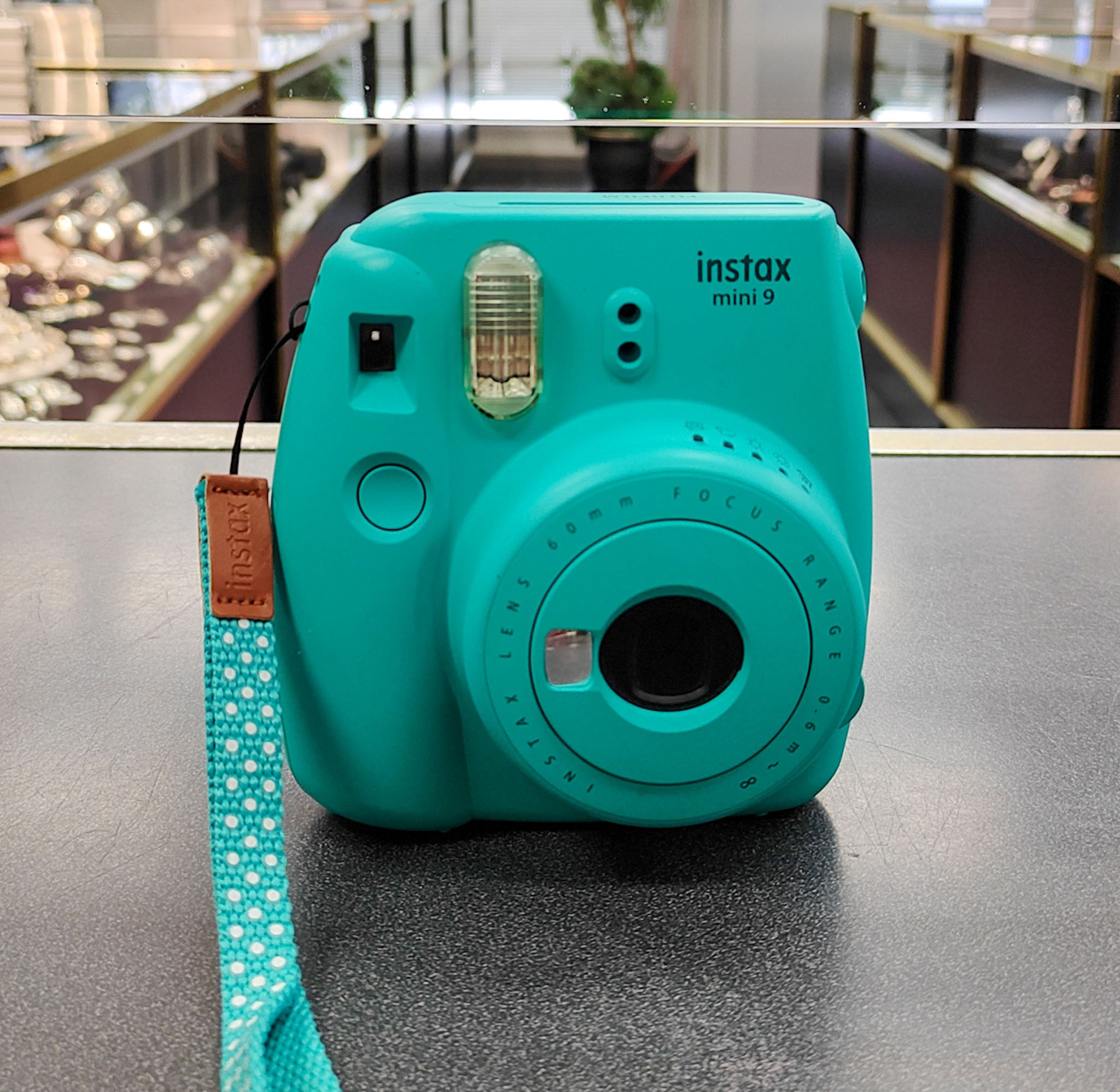 Aqua Fujifilm Instax Mini 9 instant film camera shown from multiple angles with strap attached, lens extended, rear film