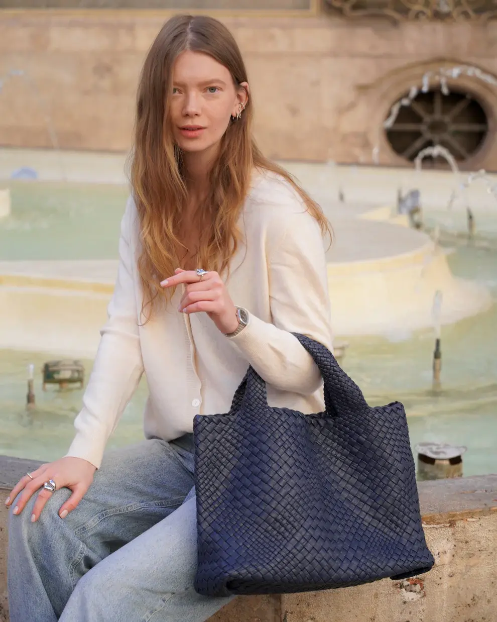 Woven navy leather tote bag worn by a woman outdoors