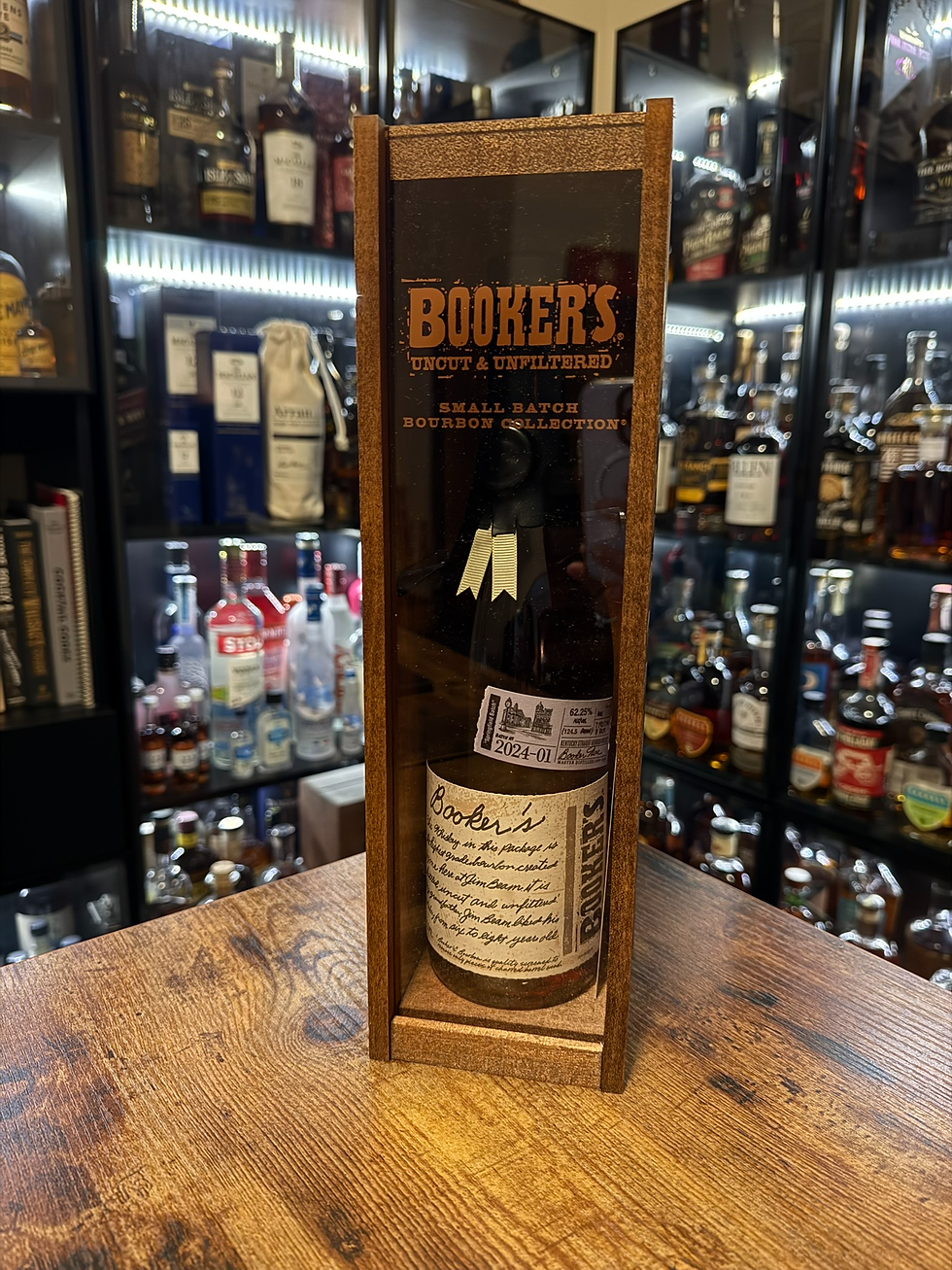 Booker's bourbon bottle in a wooden gift box on a table, with liquor shelves blurred behind.