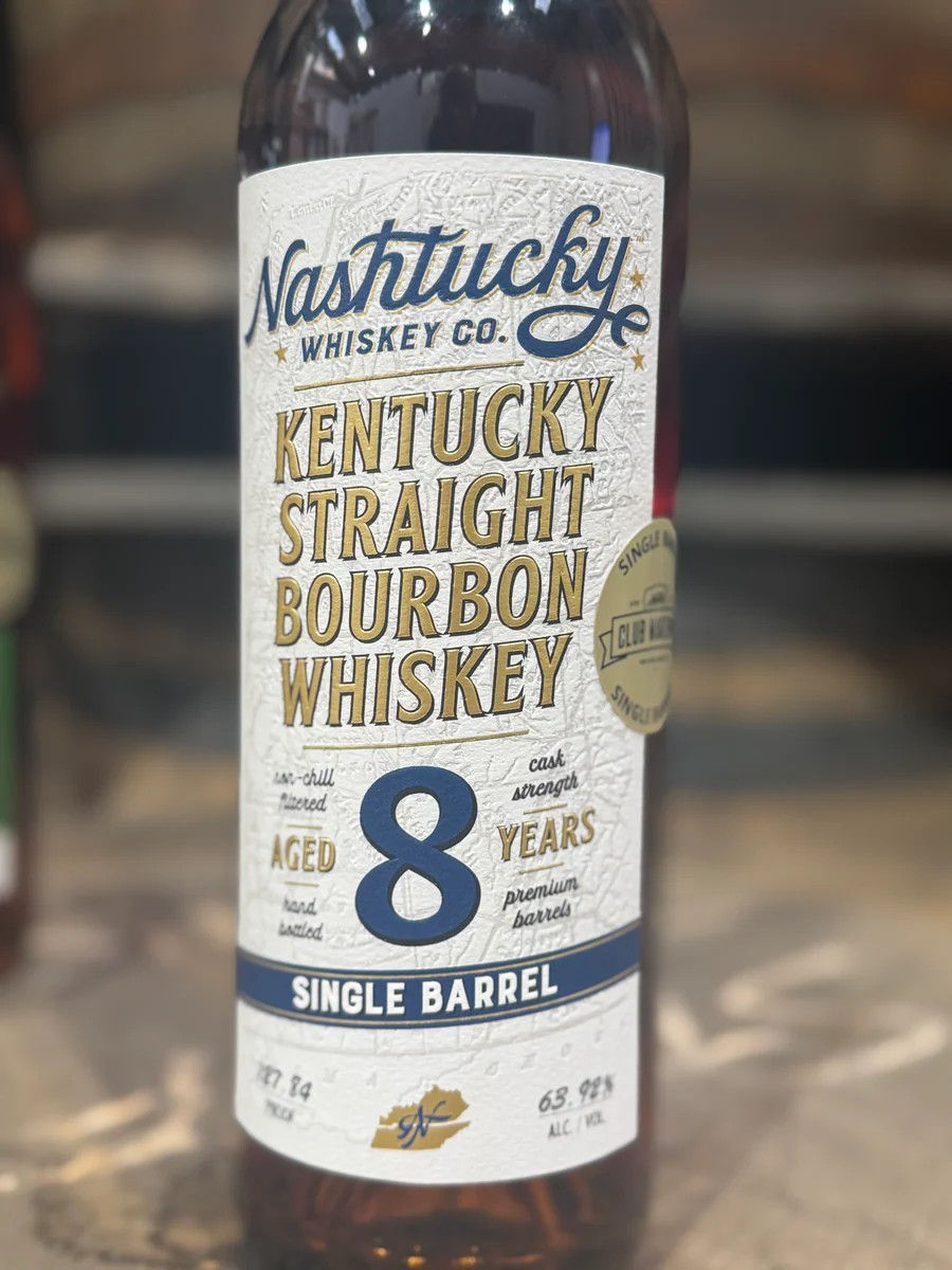 Close-up of a Nashtucky Whiskey Co. Kentucky straight bourbon bottle label, aged 8 years, single barrel, on a bar counter.
