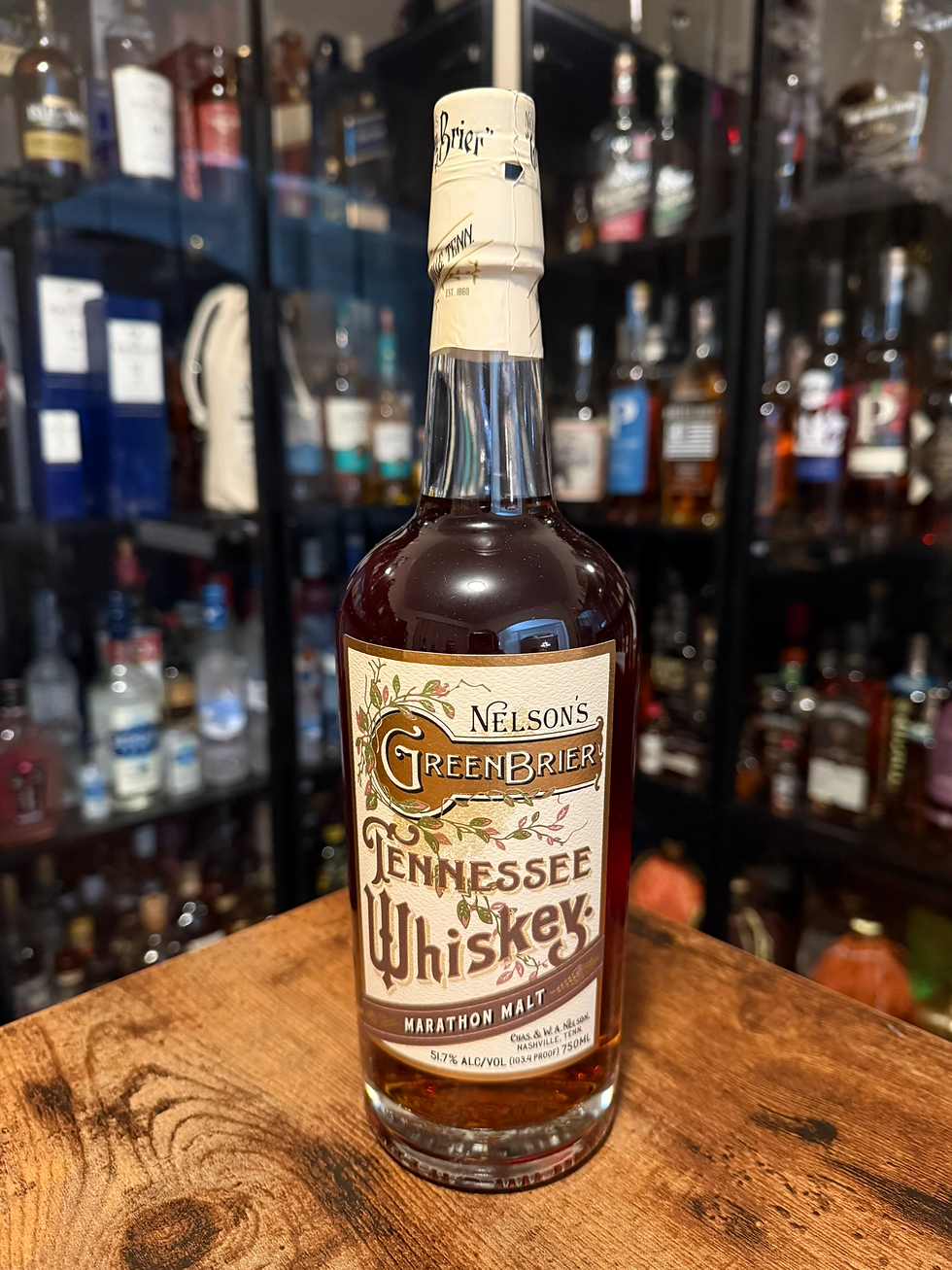 Bottle of Nelson's Green Brier Tennessee Whiskey on a wooden table, with blurred liquor shelves behind.