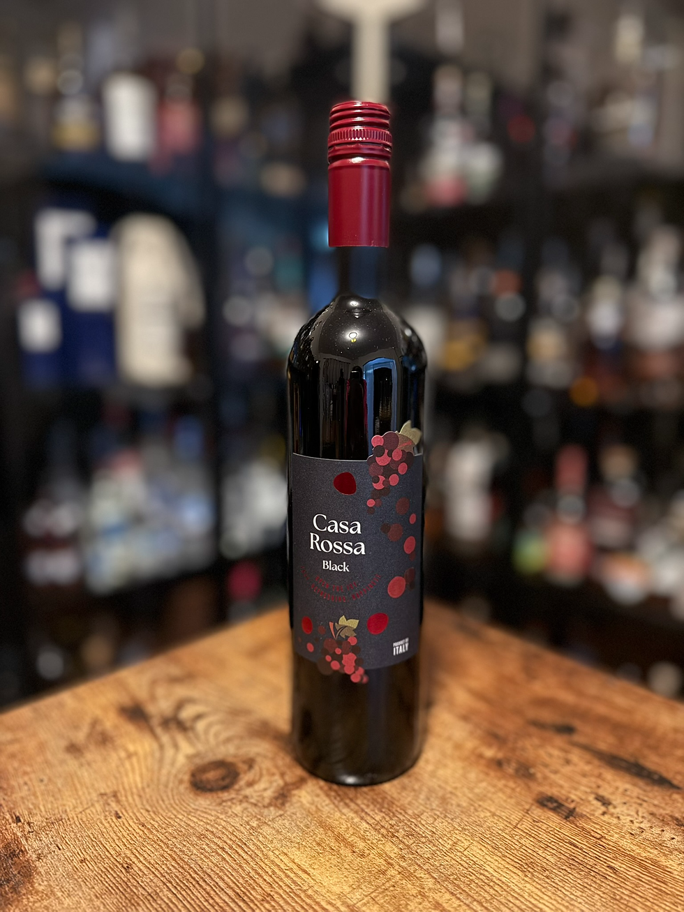 Black wine bottle on a wooden table with a red cap, label reading Casa Rossa Black, blurred bottles in the background.